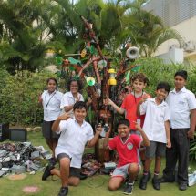 Trio Students pose before tree built of e-waste