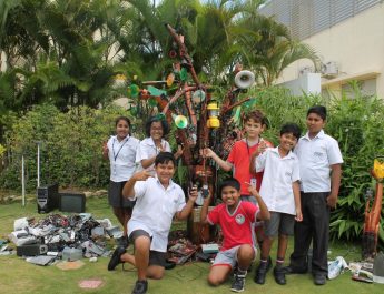 Trio Students pose before tree built of e-waste