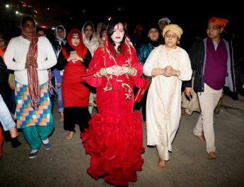 Radhe Maa in a red mermaid outfit - replete with a red purse and surrounded by devotees